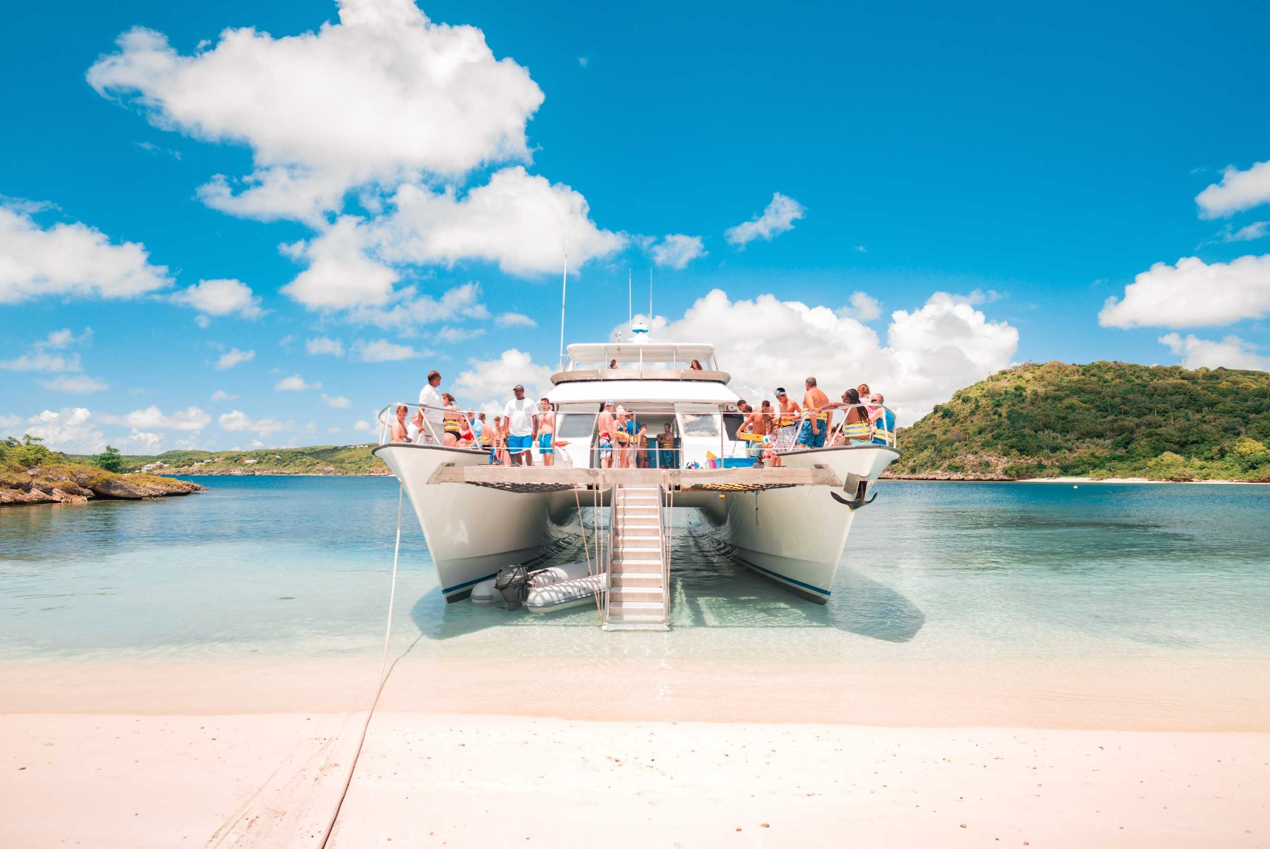 Tour boat pulled up to a sandy beach in Antigua