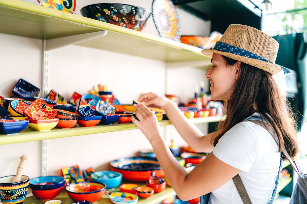 Shopper examining colorful painted bowls and crafts