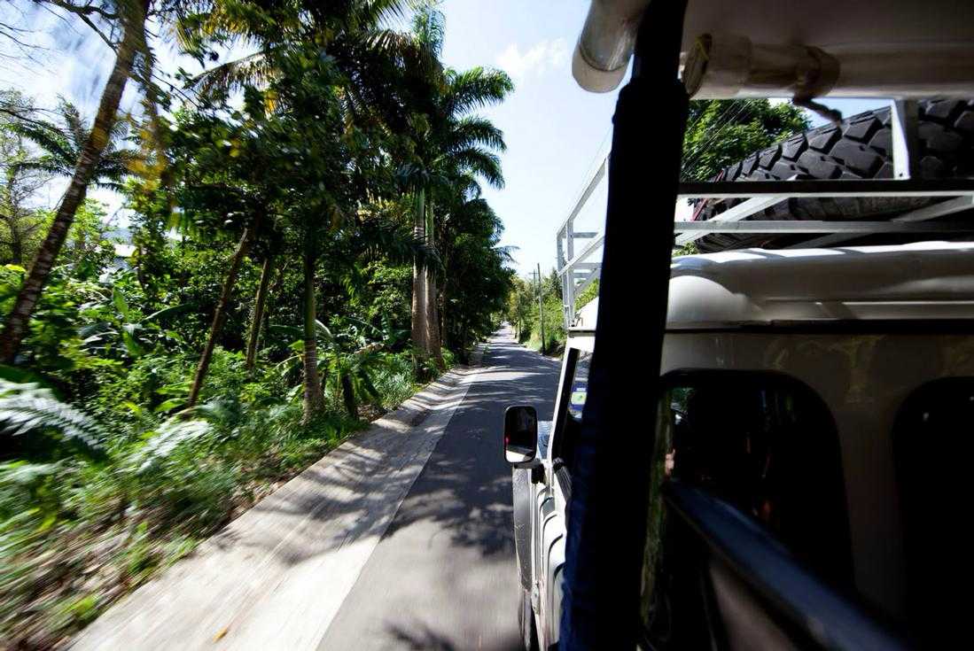 Travelers riding through tropical Antigua in an open-air safari vehicle