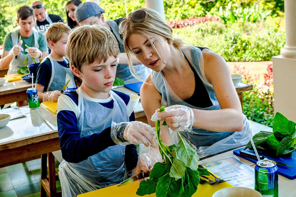 Adult and child preparing fresh herbs during a Jamaican cooking class